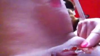 Naked aroused female pleasures herself with canine between her thighs